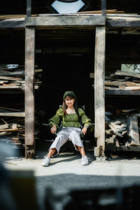 Portrait of asian woman in a green shirt relaxing sitting on chair in wooden store, close up.