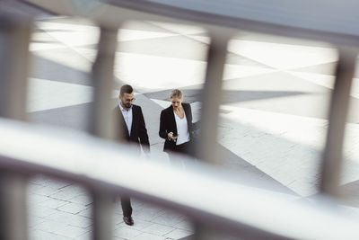 High angle view of male and female entrepreneurs talking while walking outdoors