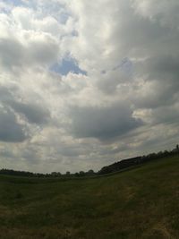 Scenic view of grassy field against cloudy sky