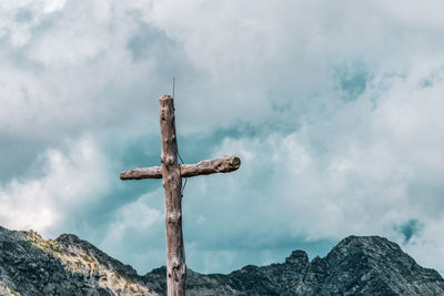 Low angle view of cross on rock against sky