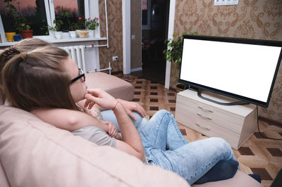 Midsection of woman sitting on sofa at home