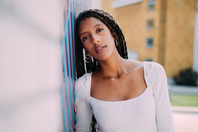 Portrait of smiling young woman leaning on wall