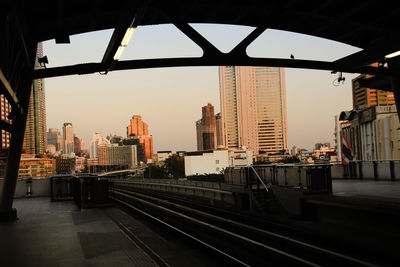 Railroad tracks by buildings in city against sky