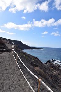 Scenic view of road by sea against sky