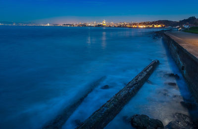 Aerial view of illuminated sea against blue sky