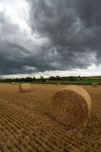 Hay bales on field against sky