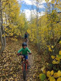 People riding bicycle amidst trees during autumn