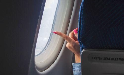 Cropped image of hand against airplane window