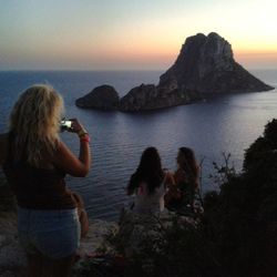 Couple sitting on cliff by sea