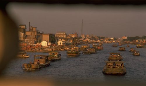 Boats in river in city against sky