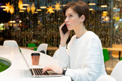 Serious woman talking on phone in shopping mall