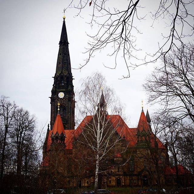 building exterior, architecture, built structure, place of worship, tree, religion, bare tree, church, spirituality, low angle view, tower, branch, steeple, sky, cathedral, clock tower, tall - high, spire