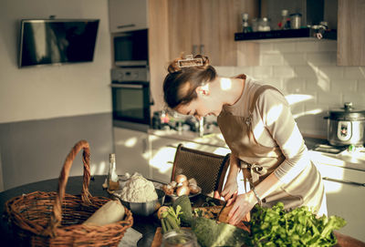 Shoot of athletic woman cutting pumpkin with a knife to prepare in the kitchen at home