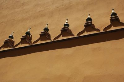 Low angle view of birds perching on wall