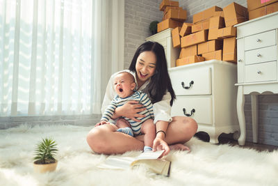 Mother reading book to toddler while sitting on fur at home