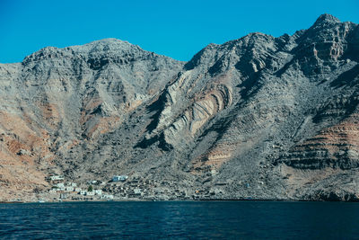 Scenic view of sea and mountains against clear blue sky