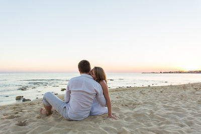 Rear view of couple sitting on beach