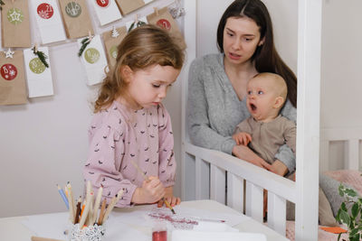 Toddler child writing christmas letter and doing advent calendar tasks in kids room. festive family