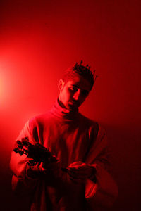 Portrait of man holding red flowers against red background