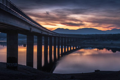 Bridge over river against sky during sunset