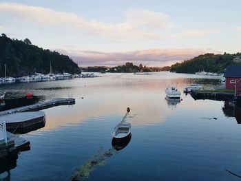 Boats moored in lake against sky during sunset