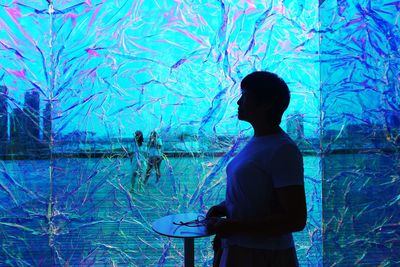 Rear view of silhouette man standing against blue sea