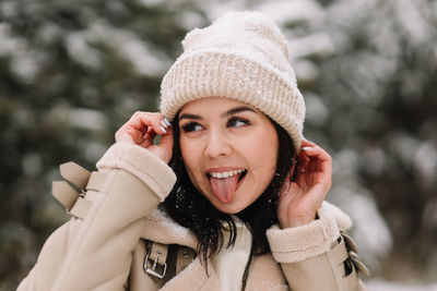 A large portrait of a smiling girl in a warm hat laughing and walking in a snowy park in winter