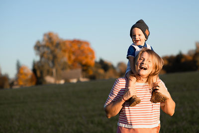 Happy mother carrying son on shoulders while standing in park