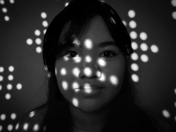 Close-up portrait of smiling woman with light on face