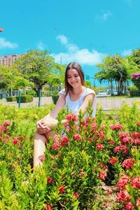 Young woman smiling while standing by flower plants