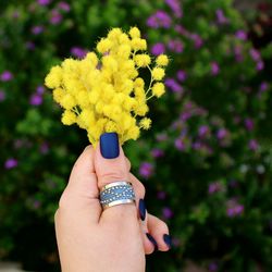 Close-up of woman hand holding yellow flowering plant