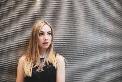 Woman looking away against wall