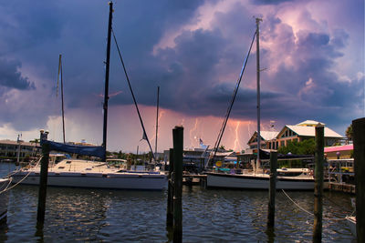 Sailboats moored at harbor against sky during sunset