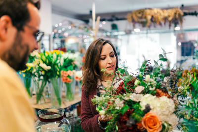 Rear view of man with woman holding bouquet at store