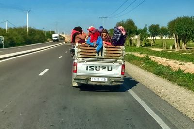 Rear view of people riding motorcycle on road