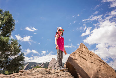 Woman standing on rock against sky