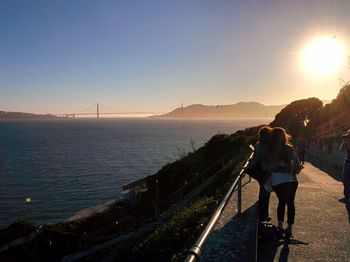 Rear view of people on footpath by san francisco bay