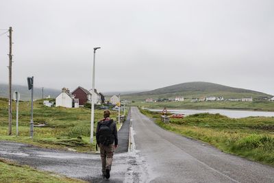 Rear view of man walking on road