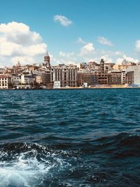 Sea by buildings against blue sky