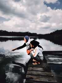 Man sitting on lake against sky