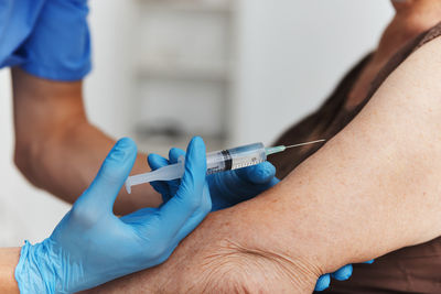 Midsection of doctor injecting vaccine to patient