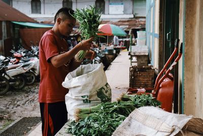 Full length of man holding vegetable standing at market