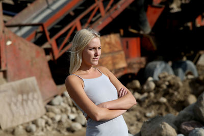 Woman standing with arms crossed while looking away against machinery