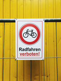 Close-up of warning sign on yellow wall