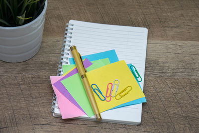 High angle view of office supplies with potted plant on wooden table