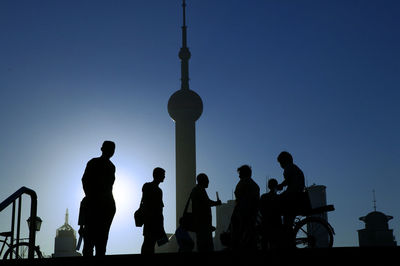 Low angle view of silhouette people sitting against clear sky