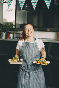 Portrait of smiling owner holding indian food plate against commercial land vehicle