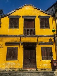 Low angle view of yellow residential building against sky