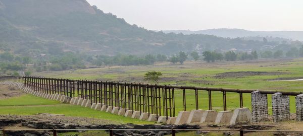 Fence on field by mountains against sky