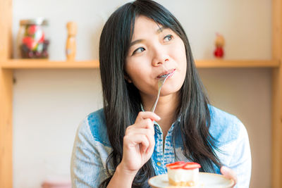 Portrait of young woman holding ice cream at home